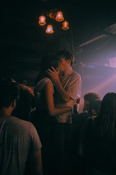 two people kissing each other while standing in front of a crowd at a music concert