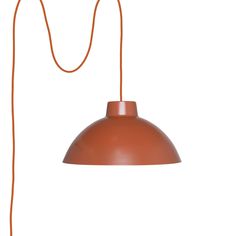 an orange light hanging from a cord on a white wall with a black lamp in the background