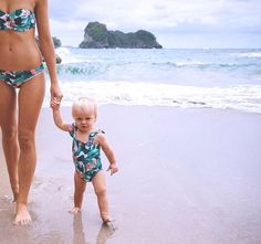 a mother and her toddler walking on the beach