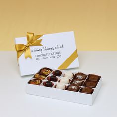 a white box filled with chocolates next to a yellow and white sign that says congratulations