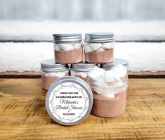 several jars filled with marshmallows on top of a wooden table