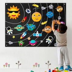 a young boy is playing with toys in front of a wall hanging on the wall