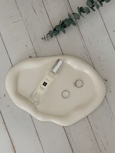 a white sink sitting on top of a wooden floor next to a bottle of cologne