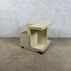 a small white table sitting on top of a carpeted floor next to a wall