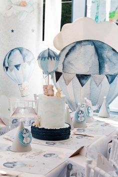 a table topped with a white cake and hot air balloons on top of the table