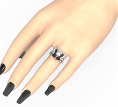 a woman's hand with black and white nail polish holding a ring on it