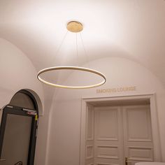 a circular light fixture hangs from the ceiling above a toilet in a small room with white walls and doors