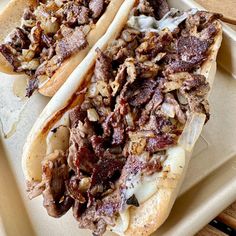 two hot dogs on buns with meat and onions