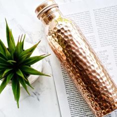 a bottle sitting on top of a table next to a plant