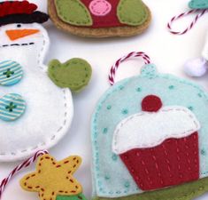 some felt ornaments are laying out on the table next to each other, including one snowman and two cupcakes