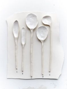 four spoons are lined up on a piece of paper with white icing attached to them