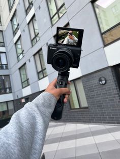 a person is holding up a camera to take a photo in front of a building