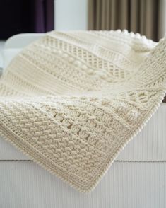 a white crocheted blanket sitting on top of a bed