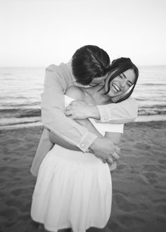 two people hugging each other on the beach