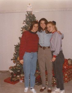 three women standing in front of a christmas tree