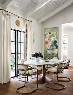 a dining room table with four chairs and a bowl of fruit on the centerpiece