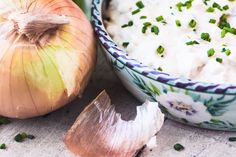 an onion and garlic dip is in a bowl next to some cloves on the table