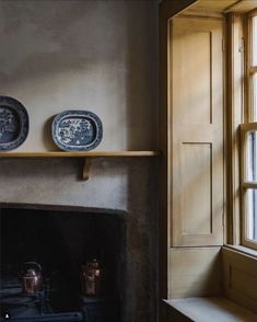 two blue and white plates sitting on top of a shelf next to a fireplace in a living room