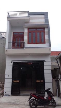 a motorcycle parked in front of a white building with red shutters and balconies