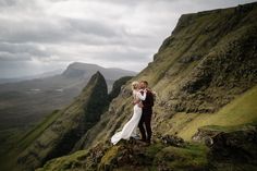 a bride and groom standing on top of a mountain