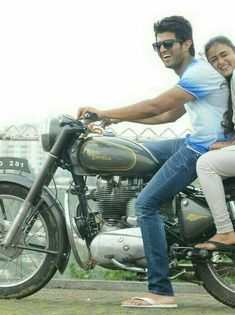 a man riding on the back of a motorcycle with a woman sitting on his seat