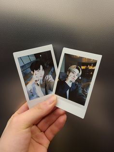 two polaroid photos being held up in the air