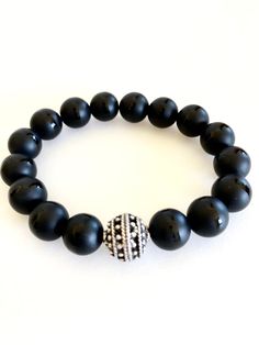 "Matte Tibetan black onyx stretch bracelet with beaded pewter focal bead accent. 10mm grade A Tibetan black onyx gemstones are matte with polished band through the middle. That are all natural stones. Accent is 12mm beaded Greek ball in antique silver pewter. Made in USA. Made to order on stretch elastic. When selecting size please add 3/4\" to 1\" to your actual wrist measurement for a comfortable fit. Black onyx is known as a powerful stone of protection." Black Onyx Stretch Bracelet With 8mm Beads, Black Onyx 8mm Beads Stretch Bracelet, Round Onyx Stretch Bracelet With 8mm Beads, Adjustable Black Onyx Bead Stretch Bracelet, Adjustable Onyx Stretch Bracelet With Black Beads, Adjustable Onyx Stretch Bracelet With Round Beads, Black Spiritual Stretch Bracelet With Polished Beads, Black Stretch Bracelet With Spacer Beads As Gift, Black Gemstone Beads Stretch Bracelet