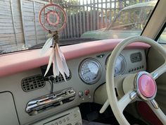 the interior of an old car is decorated with pink and white ribbons, steering wheel controls, and dashboard gauges