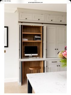 a desk with a computer on top of it next to a bookcase and cabinets