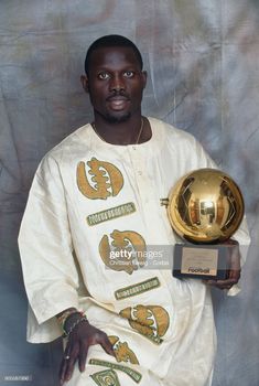 a man holding an award in front of a gray background with the words golden ball on it