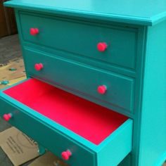 a green dresser with red drawers on the bottom and pink drawer pulls down from it