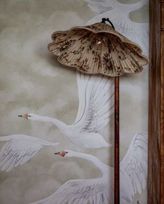 an umbrella with two birds painted on the wall next to a lamp in front of it