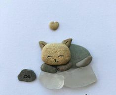 a rock with a cat sleeping on top of it next to some rocks and a heart