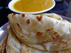 some tortillas on a plate with a bowl of soup in the back ground