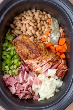 a bowl filled with meat, beans and veggies next to a wooden table