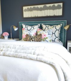 a bed with white sheets and pillows in a room