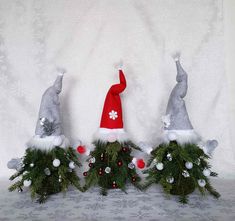 three gnomes are sitting on top of christmas decorations