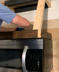 a man is working on the top of a microwave