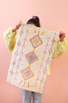 a woman holding up a large piece of art that looks like a rug with squares and rectangles on it