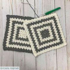 two crocheted squares are hanging on a white wooden background with green scissors and yarn