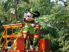 a mickey mouse statue on top of a wooden platform in the middle of some trees