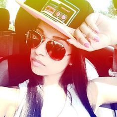 a woman wearing sunglasses and a hat in the back seat of a car with a radio on her head