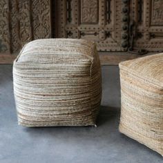 two woven stools sitting next to each other on a cement floor in front of an old wooden door