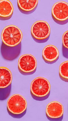 grapefruit cut in half and placed on a purple surface with other grapefruits