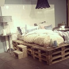 a bed made out of wooden pallets with pillows and blankets on top of it