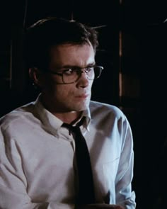 a man wearing glasses and a tie in the dark