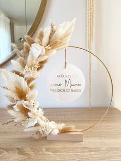 a white and gold feather wreath on a wooden table with a mirror in the background