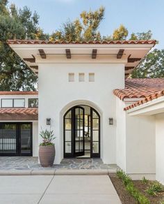 a white house with a large potted plant on the front door and entry way