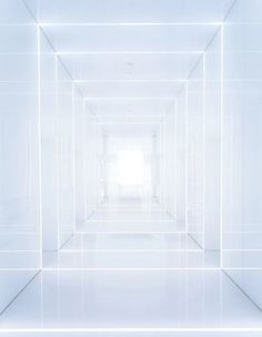 an empty white room with light coming in from the ceiling and floor to the wall