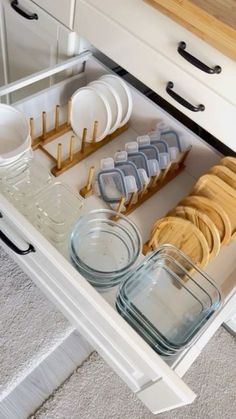 an open drawer in a kitchen filled with dishes